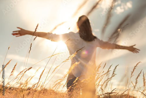 Woman enjoying the sun feeling joyful with open arms standing in a field	