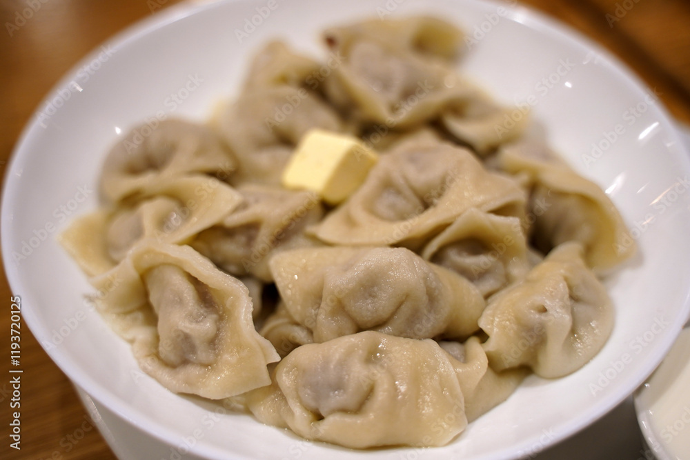 Cooked Russian dumplings with butter in a white plate on a wooden rustic table. Cooked Russian dumplings with butter in a white plate on a wooden rustic table.