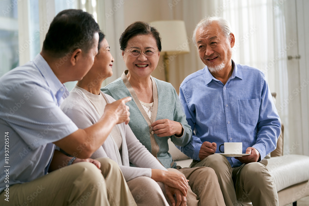 Obraz premium two happy senior asian couples sitting and chatting on couch at home