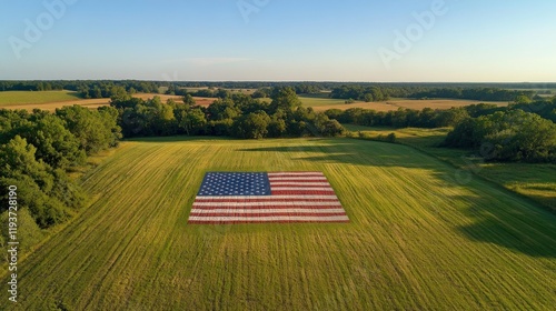 An aerial view of a giant American flag constructed in a green field during the day