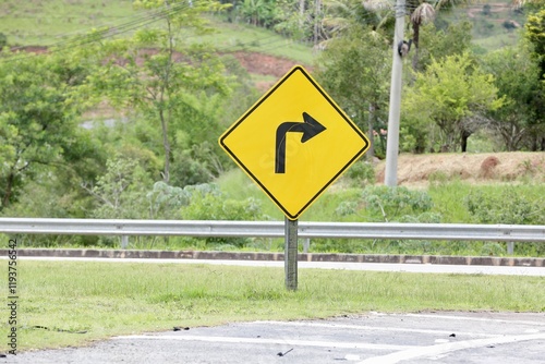 Placa de sinalização de transito vire a direita na cor amarela com fundo desfocado de uma casa. photo