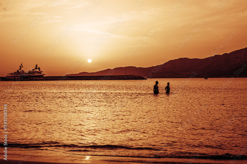 Beautiful sunset with red colors on the sea with a man and a woman walking in the water