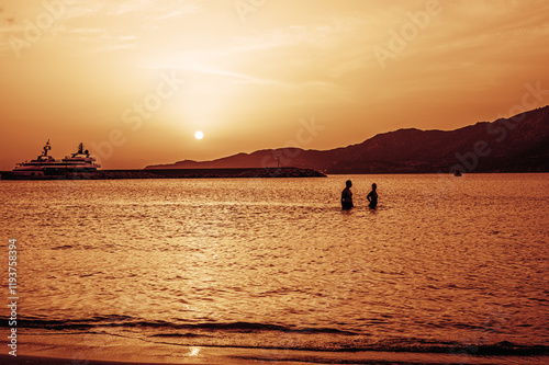 Obraz na płótnie Beautiful sunset with red colors on the sea with a man and a woman walking in the water w salonie