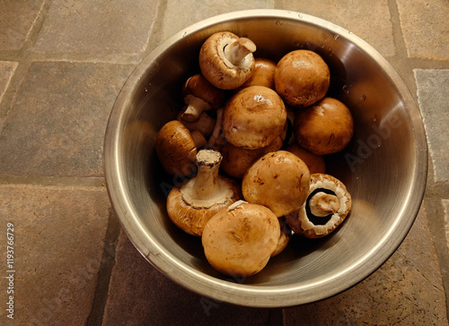 stainless steel bowl of freshly washed whole brown bella mushrooms