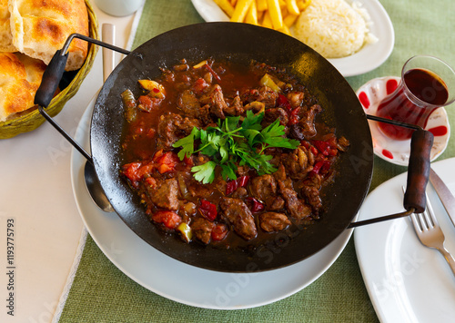 Traditional meat dish of Turkish cuisine is Sac Kavurma, cooked from lamb with vegetables in a special frying pan and ..decorated with herbs on top photo