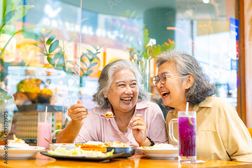Happy Asian senior woman travel and shopping in the city on summer holiday vacation. Group of Healthy elderly women friends enjoy outdoor lifestyle having lunch eating food together at restaurant.