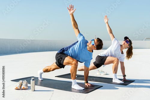 Couple practicing yoga on a rooftop during sunny afternoon photo