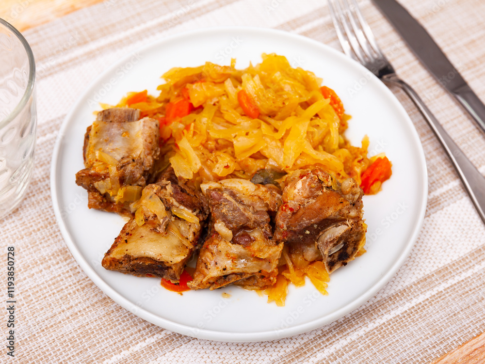 Portion of pork meat with stewed cabbage served on plate. Portion of pork meat with stewed cabbage served on plate.