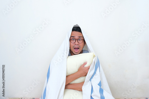 A man covered with blanket and hugging pillow screaming panic photo