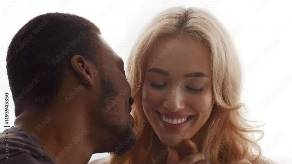 A biracial couple enjoys a tender moment together at home, exchanging smiles and affection. Their connection reflects love and warmth, showcasing their strong bond as spouses. A biracial couple enjoys a tender moment together at home, exchanging smiles and affection. Their connection reflects love and warmth, showcasing their strong bond as spouses.