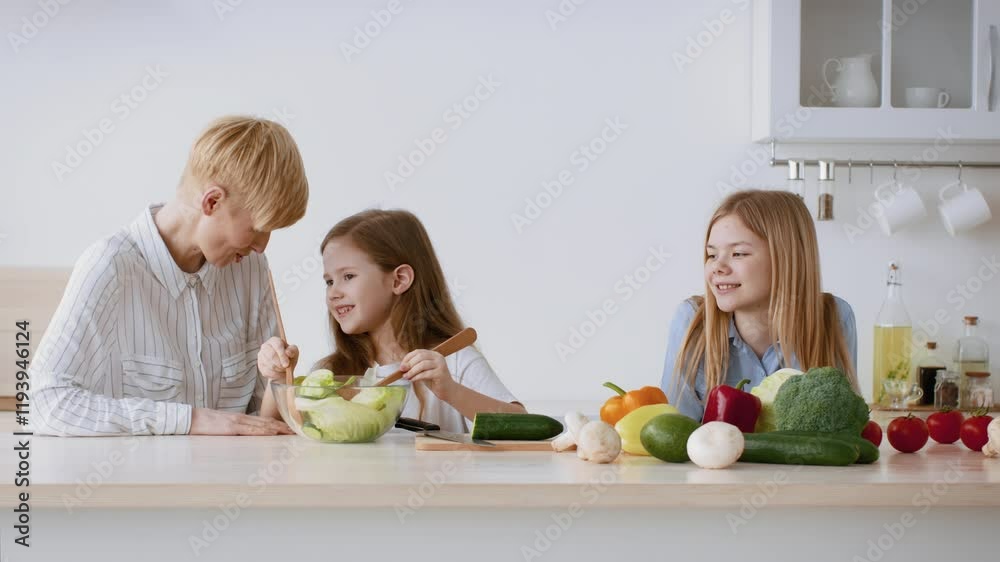In a bright kitchen, a mother and her two daughters engage in meal preparation, chopping vegetables and enjoying quality time together, fostering healthy eating habits and family bonding. In a bright kitchen, a mother and her two daughters engage in meal preparation, chopping vegetables and enjoying quality time together, fostering healthy eating habits and family bonding.
