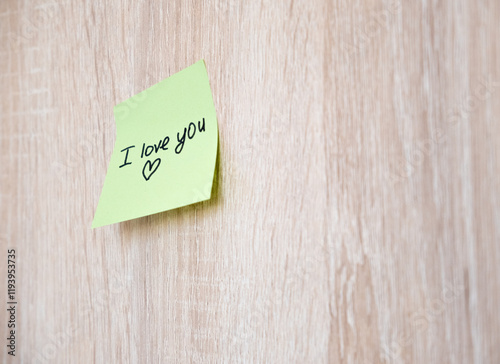 A sticker with the inscription I love you is glued to a wooden surface. There is space for text.