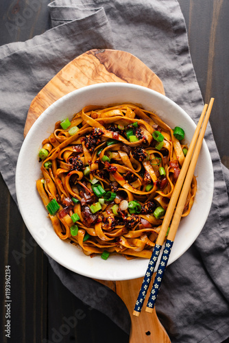Shallot Chili Oil Noodles Served in a Ramen Bowl: Hot and spicy lo mein noodles topped with chili crisp and scallions served with chopsticks