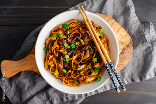 Shallot Chili Oil Noodles Served in a Ramen Bowl: Hot and spicy lo mein noodles topped with chili crisp and scallions served with chopsticks photo