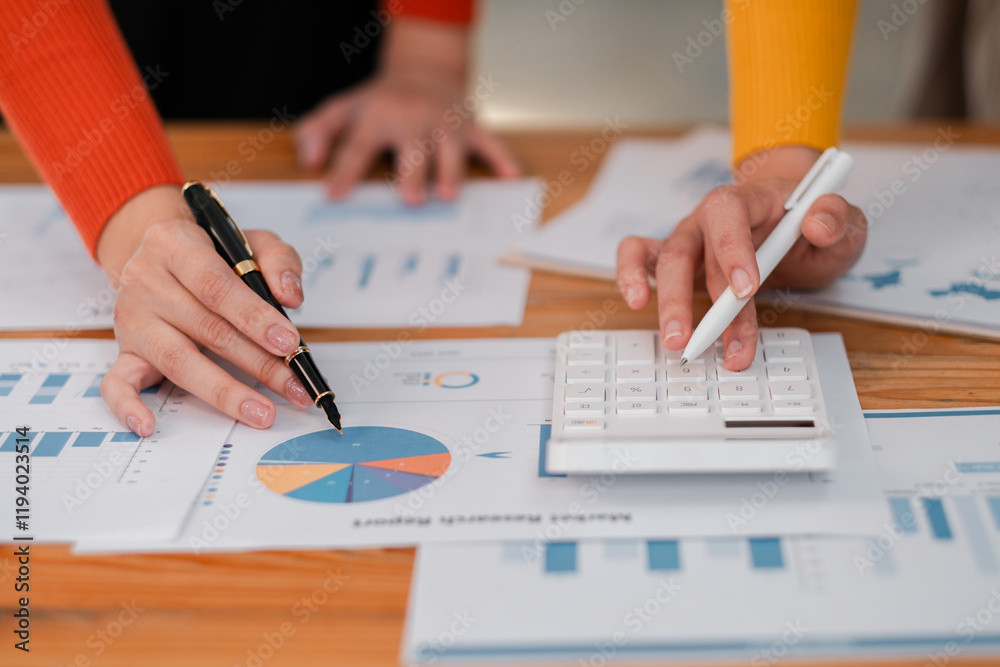 Business Professionals Analyzing Financial Reports with Charts and Calculator on Wooden Desk in Office Setting Business Professionals Analyzing Financial Reports with Charts and Calculator on Wooden Desk in Office Setting