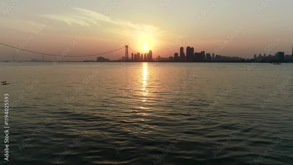 An aerial view of Wuhan's sunset river scenery, with the Yangtze River reflecting the warm hues of the setting sun, surrounded by the city's skyline and bustling riverfront An aerial view of Wuhan's sunset river scenery, with the Yangtze River reflecting the warm hues of the setting sun, surrounded by the city's skyline and bustling riverfront