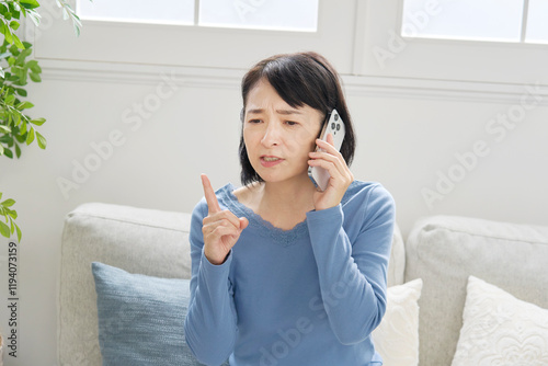スマホでクレームの電話する中年女性　リビング photo