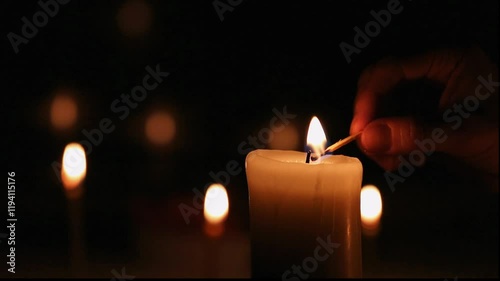 Woman lights a candle with a match on dark black background, blur lights behind in holiday celebration. Candle fire flame with space. Magic ritual with one candle fire. Close-up romantic emotion video