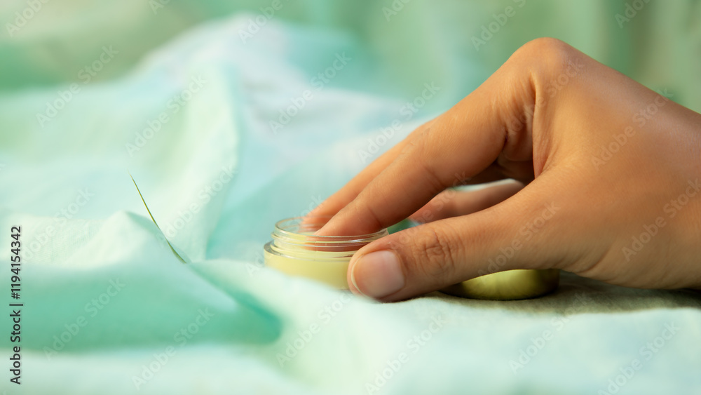 A hand taking the lip balm from the jar A hand taking the lip balm from the jar