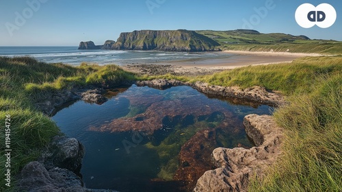 Serene Coastal Landscape with Rocky Cliffs and Tidal Pool, Vibrant Green Grass, and Tranquil Sandy Beach under Clear Blue Sky in Northern Ireland