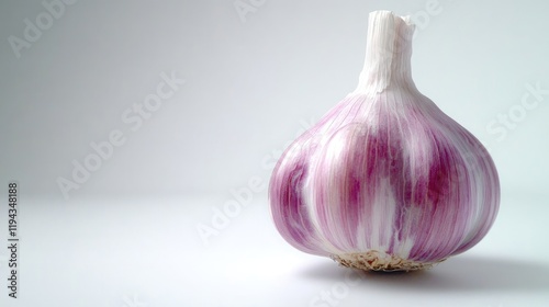 Fresh garlic bulb with distinctive purple skin isolated on a clean white background highlighting its natural texture and color. photo