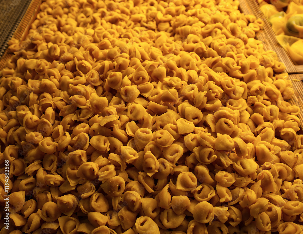 Close-up of a large pile of fresh Italian tortellini pasta in a display case.