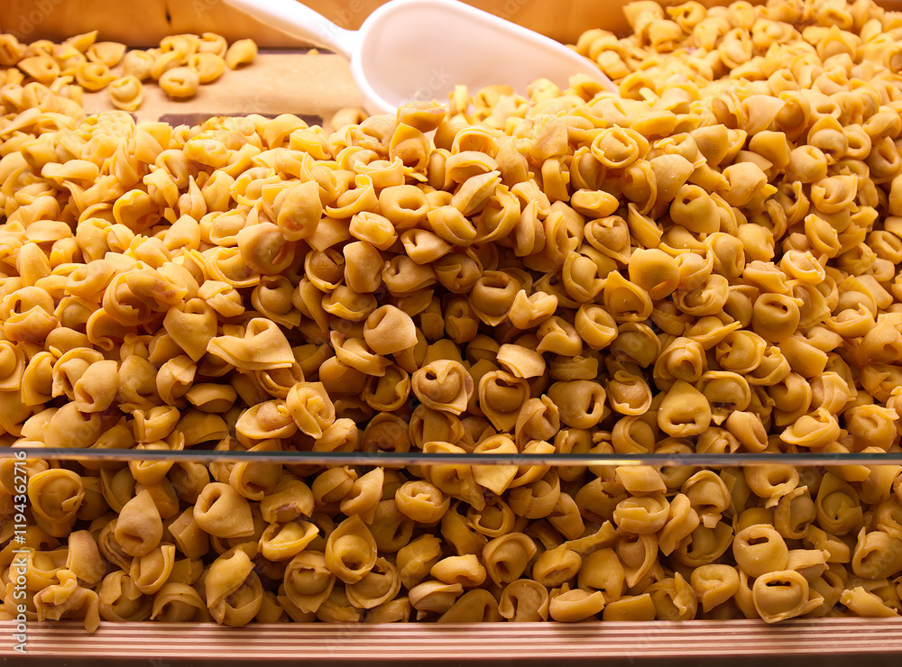 Close-up of a large pile of fresh Italian tortellini pasta in a display case.