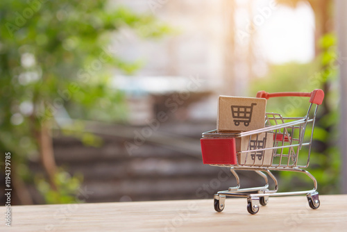 Mini shopping cart with cardboard boxes on wooden table photo