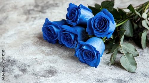 Delicate bouquet of royal blue roses, tied with a satin ribbon, resting on a light-colored table.