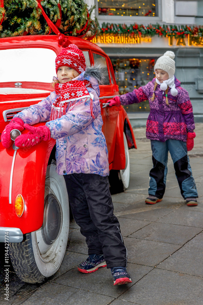 Obraz premium Two little toddler girls on a christmas market, outdoors. Happy children having fun. Holiday, lifestyle concept.