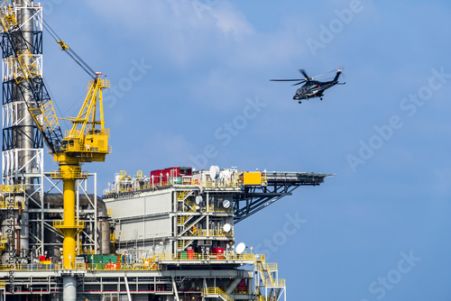 A helicopter about to land on an oil production platform for transferring of offshore crew at oil field
