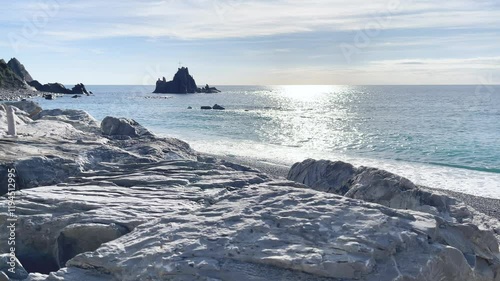 Asseu rock and sea in Liguria. Cross on rock. Riva Trigoso landmark. Reflection of sun in water in day time.  photo