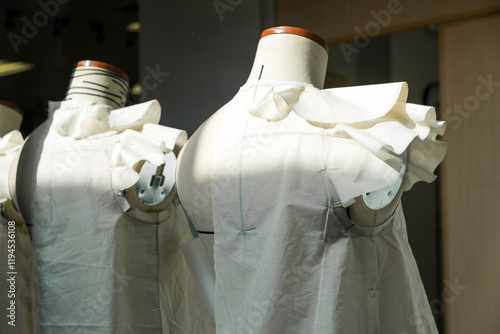 Two dress forms adorned with elegant white fabric display unique designs, showcasing the artistry and craftsmanship of fashion creation. Fashion design school business concept.