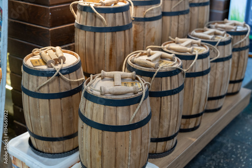 A row of wooden barrels with rope handles. The barrels are stacked on top of each other photo