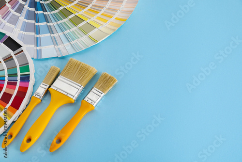 Fototapeta Naklejka Na Ścianę i Meble -  Color selection charts and paint brushes on light blue table, space for text. Decorating and design