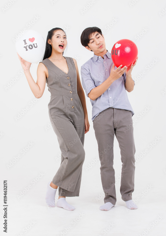 Portrait of young asian happy attractive cheerful couple love Joyful sweethearts holding air balloons for Valentine's day enjoy good time romantic posing to camera smiling standing on white background Portrait of young asian happy attractive cheerful couple love Joyful sweethearts holding air balloons for Valentine's day enjoy good time romantic posing to camera smiling standing on white background