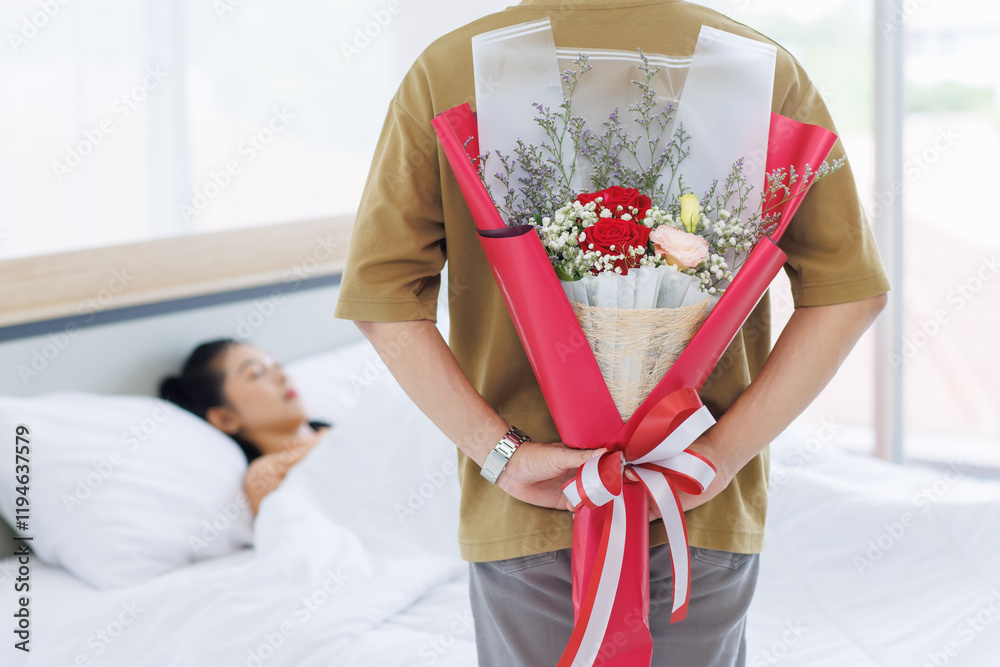 Obraz premium Asian young couple love sweet romantic happy attractive, man holding a bouquet of red roses behind his back for beloved woman sleeping on the bed in bedroom at home enjoy good time together.