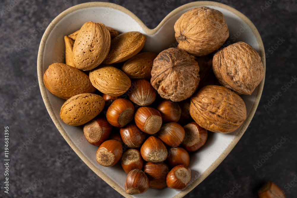 Mix of nuts in a heart shaped bowl, hazelnuts, almonds, walnuts, top view Mix of nuts in a heart shaped bowl, hazelnuts, almonds, walnuts, top view