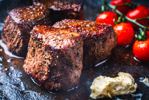 Filet mignon steaks with cherry tomatoes on a black mica plate. Close-up.