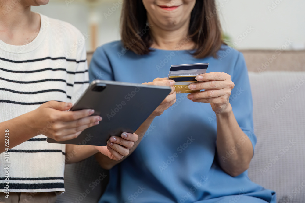 Mother and Child Enjoying Online Shopping Together Using a Tablet and Credit Card in a Cozy Home Setting Mother and Child Enjoying Online Shopping Together Using a Tablet and Credit Card in a Cozy Home Setting
