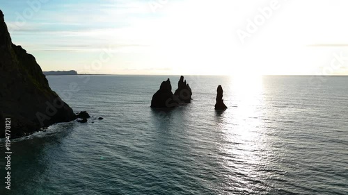 Wallpaper Mural Golden hour view of towering sea stacks along Iceland’s southern coast near Dyrhólaey, with calm waters and distant cliffs, creating a serene and stunning coastal landscape. Torontodigital.ca