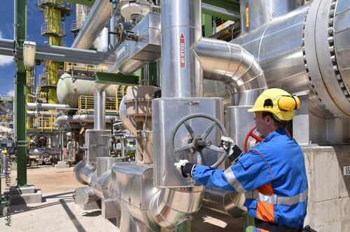 workers in an industrial plant for the production and processing of crude oil - operation of the valve/slider on the pipeline for crude oil photo