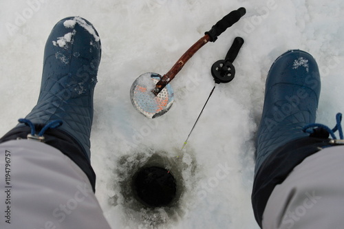 woman sitting by the hole with a fishing rod during winter fishing