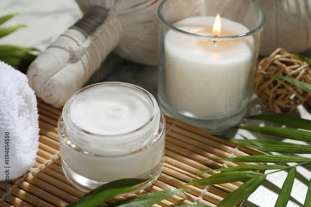 Spa composition with different cosmetic products, herbal bags, burning candle and leaves on table, closeup Spa composition with different cosmetic products, herbal bags, burning candle and leaves on table, closeup