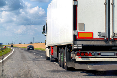 Fototapeta Naklejka Na Ścianę i Meble -  A beautiful truck transports cargo along the highway in the summer. Concept of a cargo transport company. Work and vacancies as a freight forwarder driver. Copy space for text