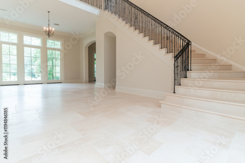 A large, empty room with a white staircase leading up to a second floor photo