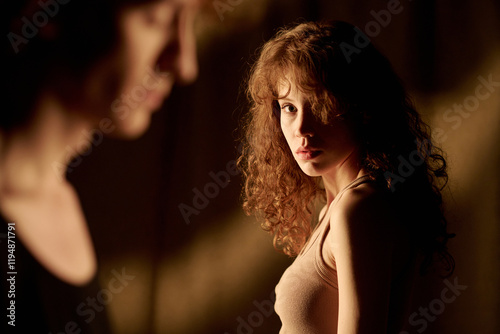 Medium close up of attractive young woman looking at her unrecognizable boyfriend sadly