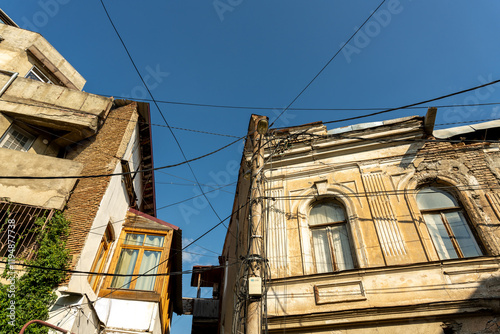 A building with a lot of wires hanging from it. The wires are connected to a power source photo