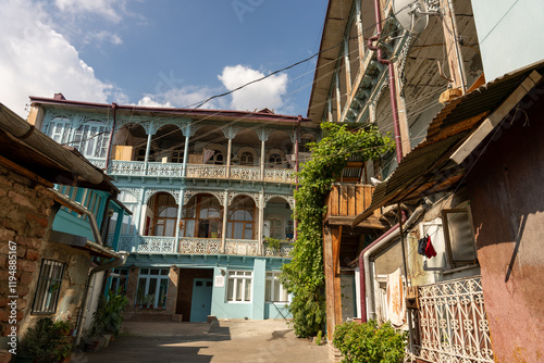 Fototapeta Naklejka Na Ścianę i Meble -  A small courtyard with a building in the background. The building has a balcony and a green ivy growing on it