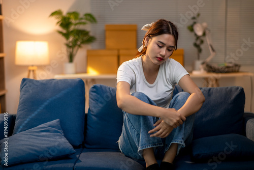 A woman is sitting on a blue couch with her hands on her knees